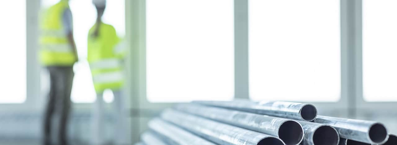 Two people in safety wear looking out through a window.